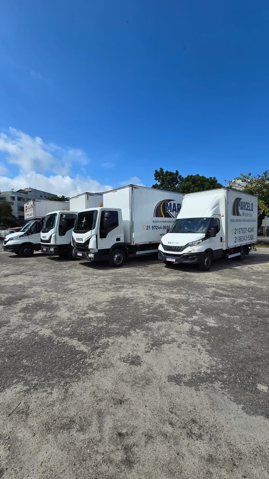 Quatro caminhões baú Iveco brancos da Marcelo Mudanças estacionados lado a lado sob céu azul